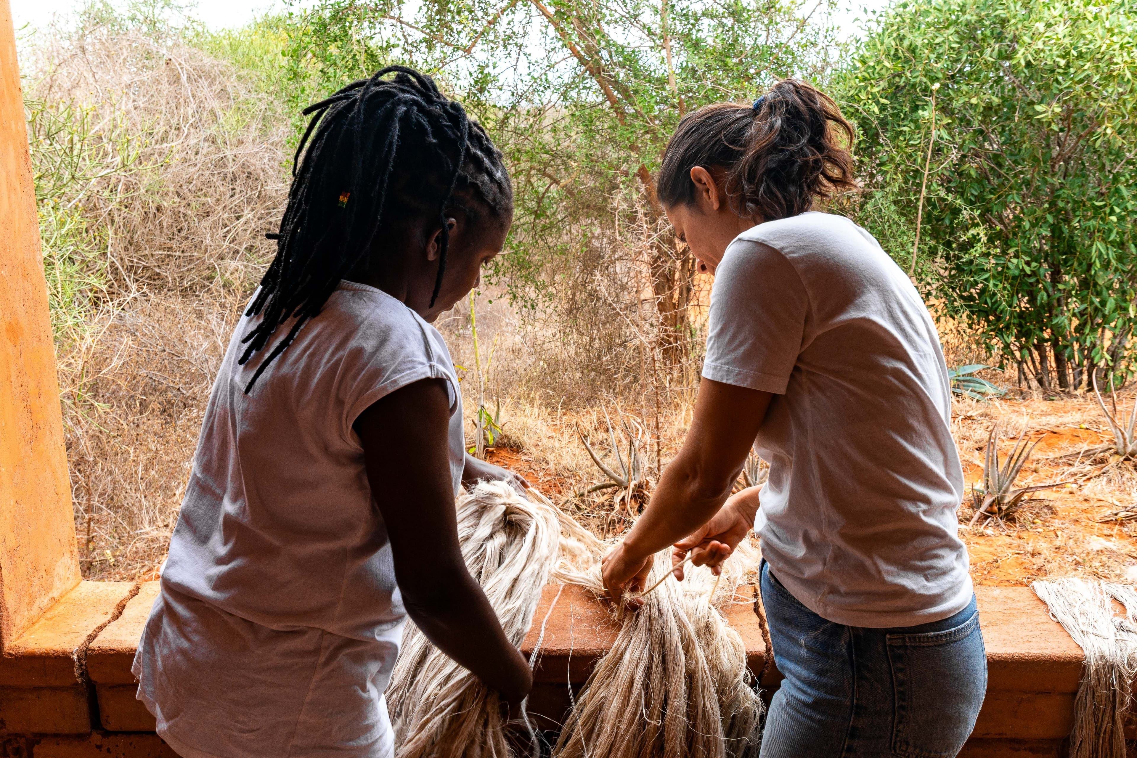 A trainer and artisan hand-sorting banana fibre strands by colour during preparation.