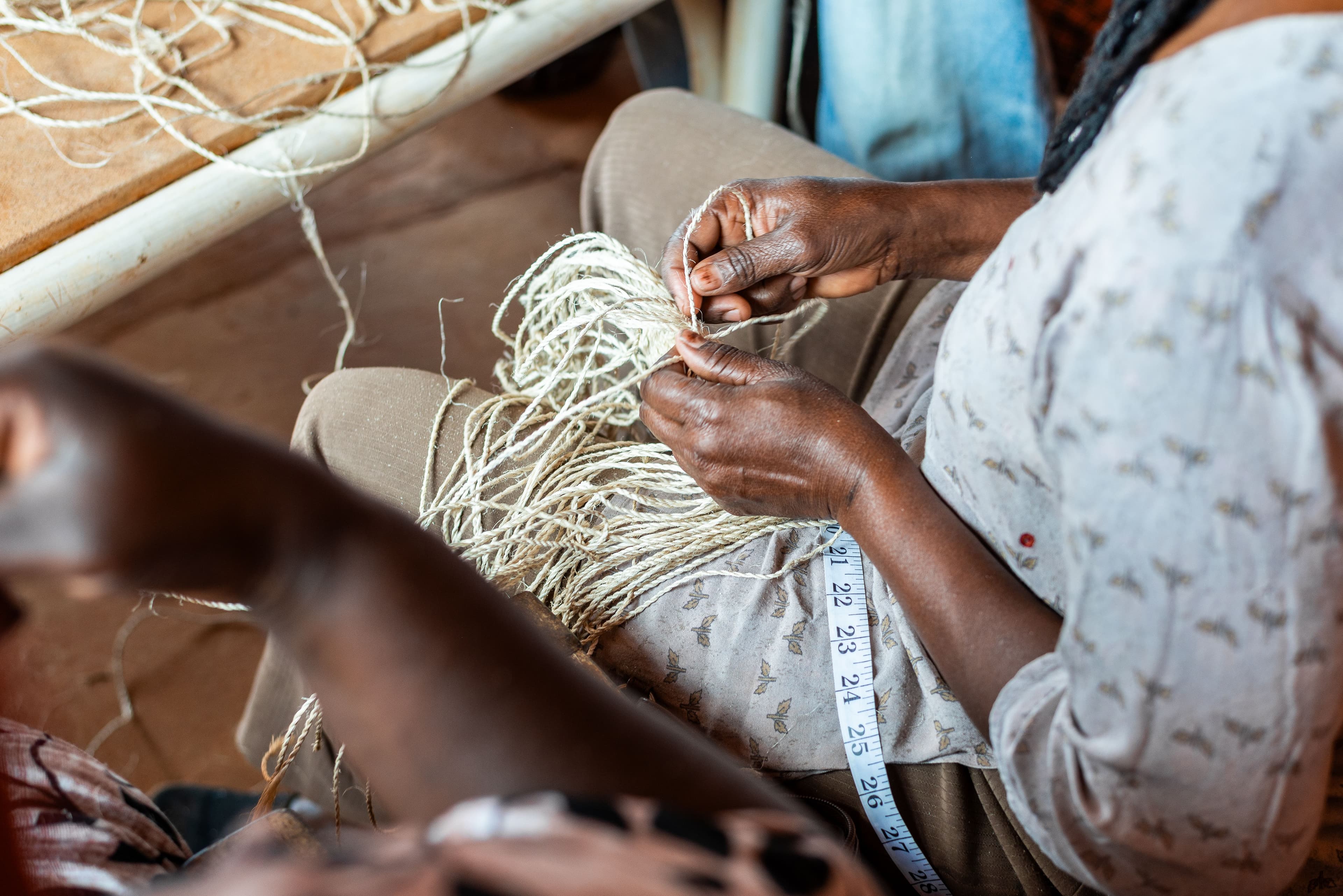 An artisan hand weaving the base of a banana fiber basket.